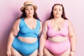 Young plus size twins wearing bikini with serious expression on face