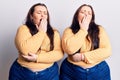 Young plus size twins wearing casual clothes bored yawning tired covering mouth with hand