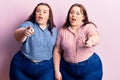 Young plus size twins wearing casual clothes pointing displeased and frustrated to the camera, angry and furious with you Royalty Free Stock Photo