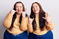 Young plus size twins wearing casual clothes shouting with crazy expression doing rock symbol with hands up