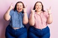 Young plus size twins wearing casual clothes shouting with crazy expression doing rock symbol with hands up