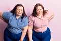 Young plus size twins wearing casual clothes suffering of backache, touching back with hand, muscular pain Royalty Free Stock Photo