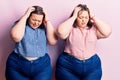 Young plus size twins wearing casual clothes suffering from headache desperate and stressed because pain and migraine Royalty Free Stock Photo