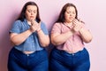 Young plus size twins wearing casual clothes suffering pain on hands and fingers, arthritis inflammation Royalty Free Stock Photo