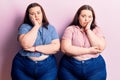 Young plus size twins wearing casual clothes thinking looking tired and bored with depression problems with crossed arms