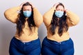 Young plus size twins wearing medical mask suffering from headache desperate and stressed because pain and migraine Royalty Free Stock Photo