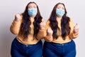 Young plus size twins wearing medical mask very happy and excited doing winner gesture with arms raised, smiling and screaming for