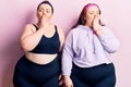 Young plus size twins wearing sportswear bored yawning tired covering mouth with hand