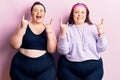 Young plus size twins wearing sportswear shouting with crazy expression doing rock symbol with hands up