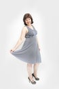 Young plus size woman in gray dress and heels on white background. Concept of body positive Royalty Free Stock Photo
