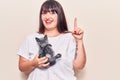 Young plus size woman holding cat smiling with an idea or question pointing finger with happy face, number one Royalty Free Stock Photo