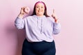 Young plus size woman holding donut smiling with an idea or question pointing finger with happy face, number one Royalty Free Stock Photo