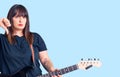 Young plus size woman playing electric guitar with angry face, negative sign showing dislike with thumbs down, rejection concept Royalty Free Stock Photo