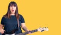 Young plus size woman playing electric guitar scared and amazed with open mouth for surprise, disbelief face Royalty Free Stock Photo