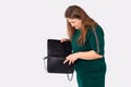 Young plus size woman searches in elegant black bag. Stylish plump blonde in green dress, looking for a wallet, keys Royalty Free Stock Photo