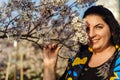 Young plus size woman smiling while covering half of her face with cherry blossom branch in spring while walking in the Royalty Free Stock Photo