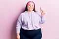 Young plus size woman wearing sportswear smiling with an idea or question pointing finger up with happy face, number one Royalty Free Stock Photo