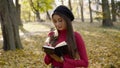 Young poetess inspects the autumn park and writes down her thoughts in notebook