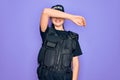 Young police woman wearing security bulletproof vest uniform over purple background covering eyes with arm smiling cheerful and Royalty Free Stock Photo