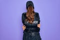 Young police woman wearing security bulletproof vest uniform over purple background Hugging oneself happy and positive from