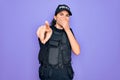 Young police woman wearing security bulletproof vest uniform over purple background laughing at you, pointing finger to the camera Royalty Free Stock Photo