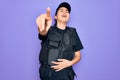 Young police woman wearing security bulletproof vest uniform over purple background laughing at you, pointing finger to the camera Royalty Free Stock Photo