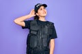 Young police woman wearing security bulletproof vest uniform over purple background smiling confident touching hair with hand up Royalty Free Stock Photo