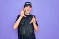 Young police woman wearing security bulletproof vest uniform over purple background smiling funny doing claw gesture as cat, Royalty Free Stock Photo