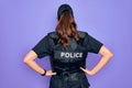 Young police woman wearing security bulletproof vest uniform over purple background standing backwards looking away with arms on
