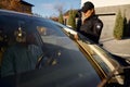 Young policewoman with tablet standing near car