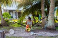 Young Polynesian woman in a hammock with mac notebook working outdoors under palm trees. .TV domain. Tuvalu, Polynesia.