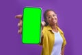 Young positive African American woman holds out green screen phone to camera Royalty Free Stock Photo