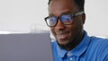 Young positive afro businessman working at desk in office with laptop. Royalty Free Stock Photo