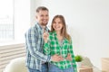 Young positive couple holding keys to a new apartment while standing in their living room. Housewarming and family Royalty Free Stock Photo