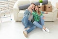 Young positive couple holding keys to a new apartment while standing in their living room. Housewarming and family Royalty Free Stock Photo