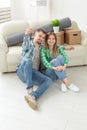 Young positive couple holding keys to a new apartment while standing in their living room. Housewarming and family Royalty Free Stock Photo