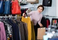 Female shopper examining warm sweaters in women cloths shop Royalty Free Stock Photo