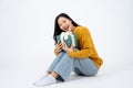 Young happy Asian woman holding a surprise gift box and sitting on a floor on a white background Royalty Free Stock Photo