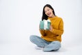 Young happy Asian woman holding a surprise gift box and sitting on a floor on a white background Royalty Free Stock Photo