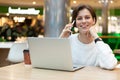 Young positive happy smiling beautiful brunette woman wearing white sweatshirt sitting at a shopping center at a table Royalty Free Stock Photo