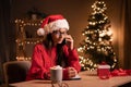 Young positive hispanic woman with smartphone doing online shopping during Christmas holidays, smiling female freelancer Royalty Free Stock Photo