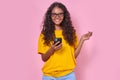 Young positive Indian woman teenager uses mobile phone stands in studio Royalty Free Stock Photo