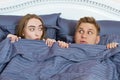 Young positive loving couple under blanket in bed and looking into eyes Royalty Free Stock Photo