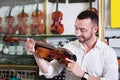 Young positive man purchasing traditional violins in store Royalty Free Stock Photo
