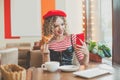 Young positive optimistic woman with red smartphone in cafe