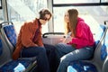 Young positive people, man and woman using public transportation, tram and looking on mobile phone, talking while riding Royalty Free Stock Photo