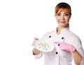 Young positive red-haired woman doctor or nurse in white medical uniform and gloves showing plate with colorful pills Royalty Free Stock Photo