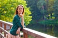 A young, positive, smiling woman stands on a wooden pier, a blurry lake landscape in the background Royalty Free Stock Photo