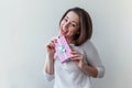 Young positive woman holding small pink gift box isolated on white background. Preparation for holiday. Girl looking Royalty Free Stock Photo