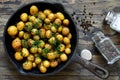 Young potatoes fried with pepper and garlic in a pan on a wooden background. Top view